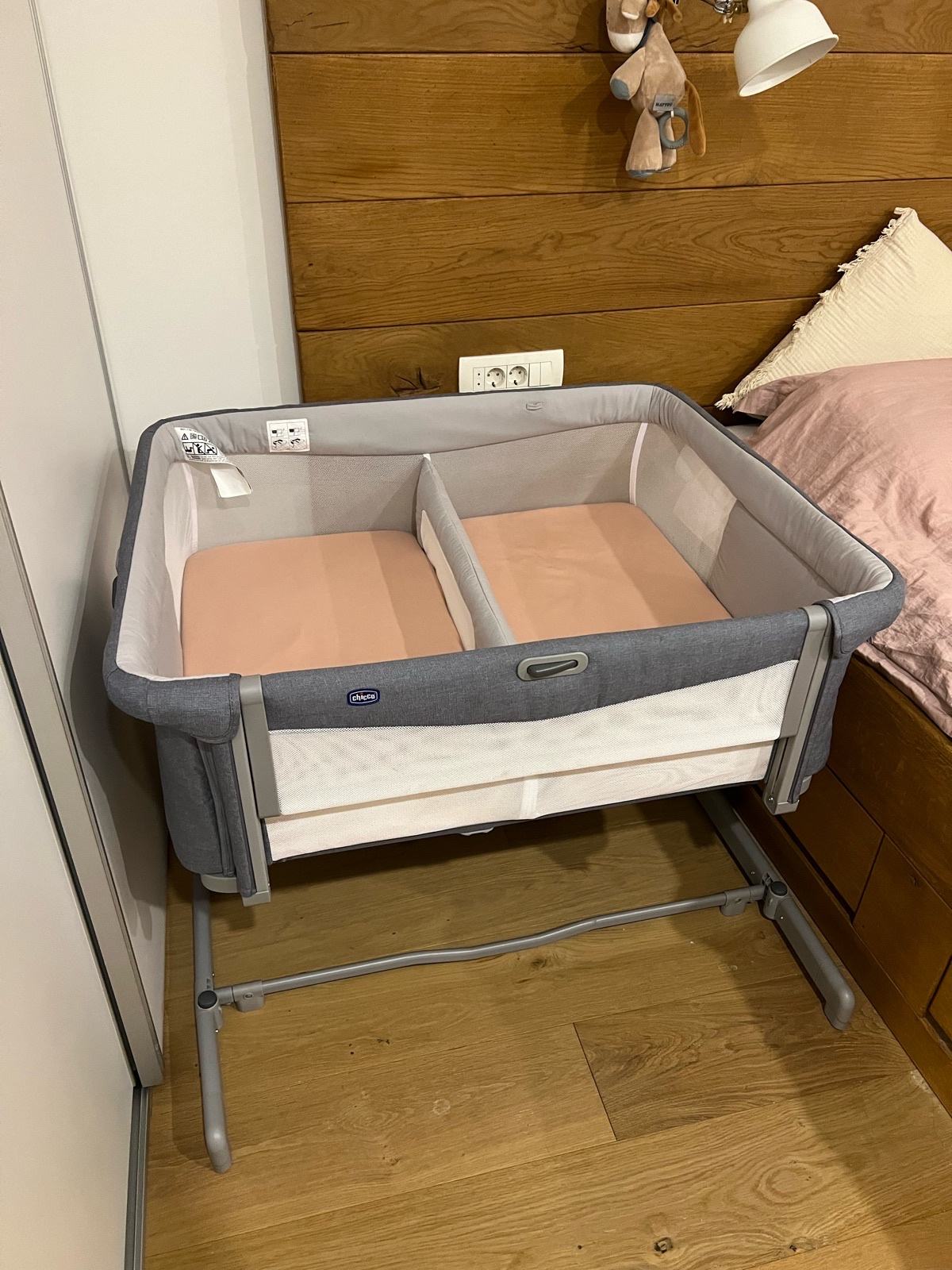 A complete pre-owned Chicco Next2Me Twins crib with divider photographed beside a bed